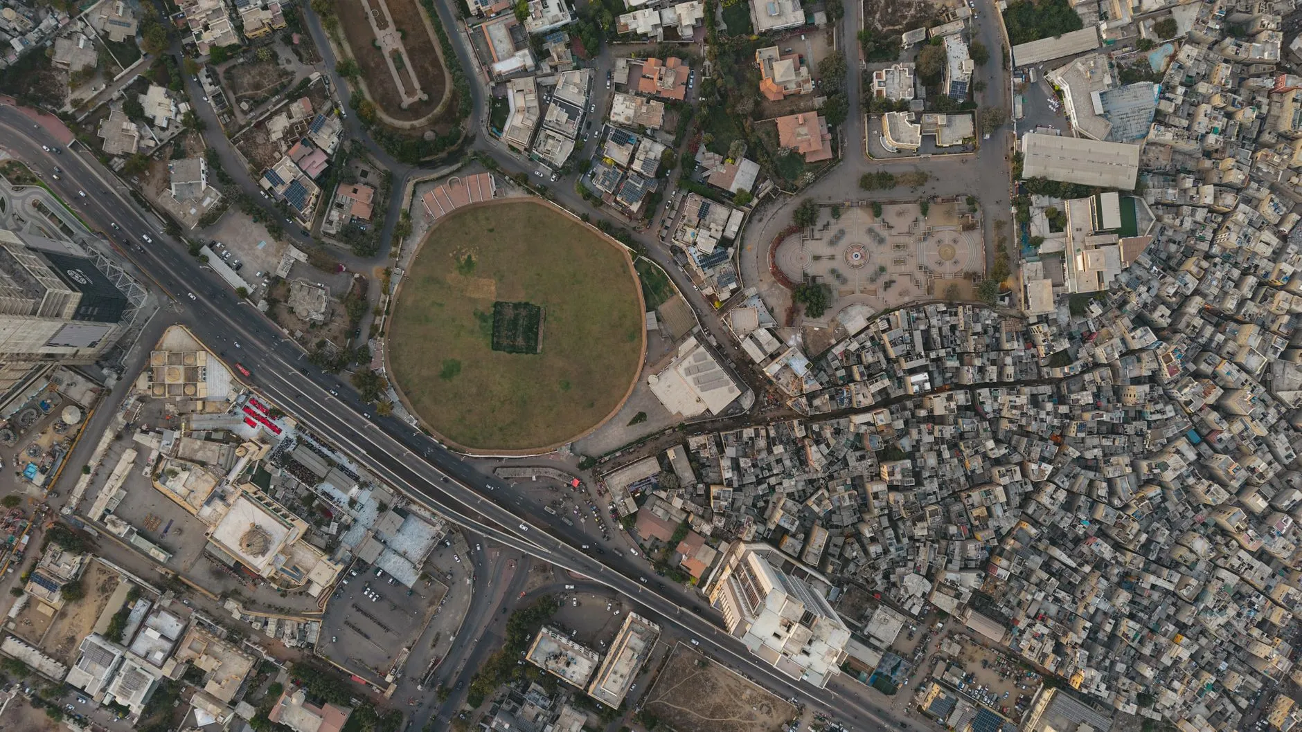 Aerial view of Karachi with a round park, flyover and dense neighborhoods