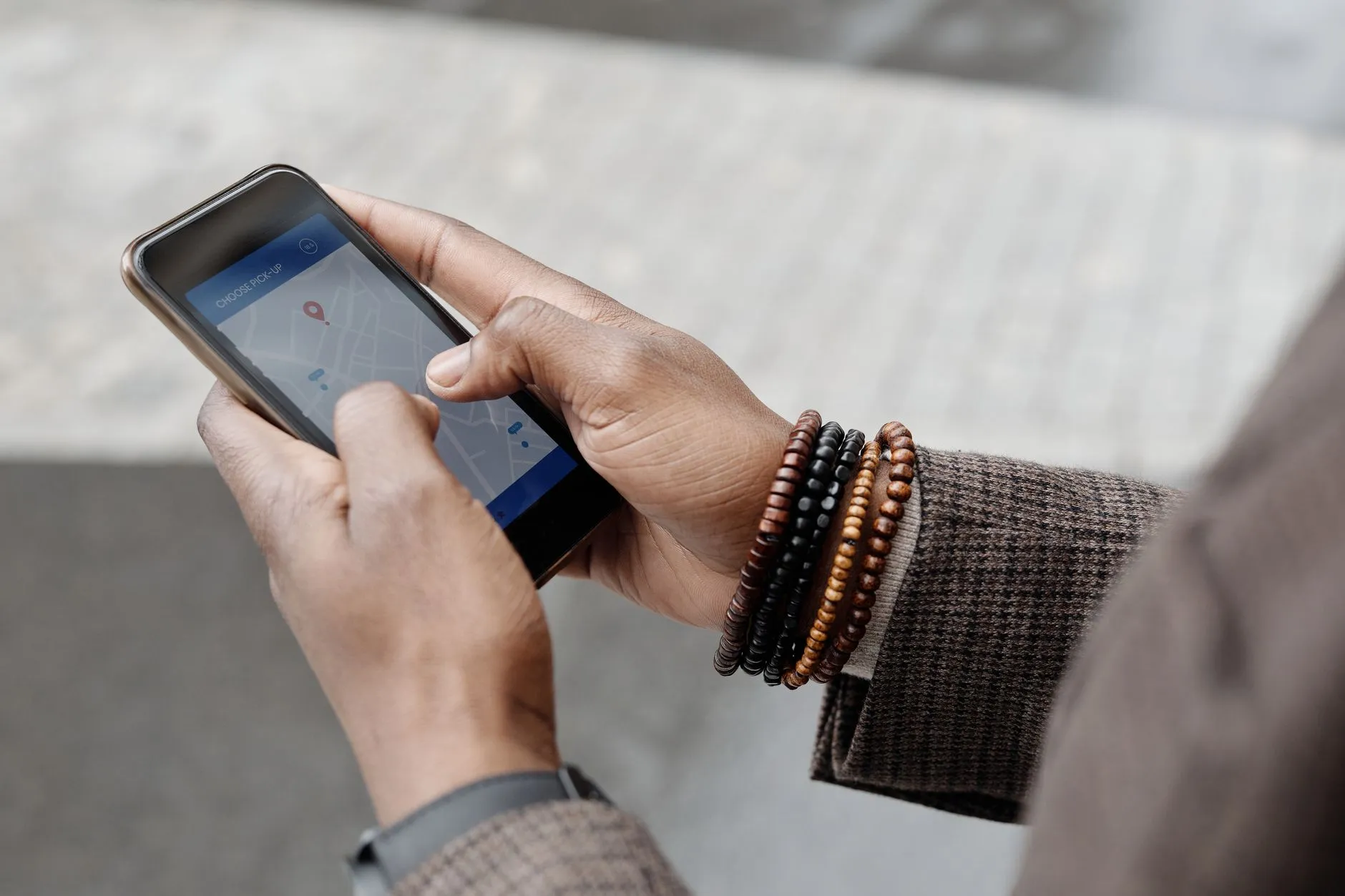 Hands holding a smartphone with a map app open outdoors, searching for a nearby business