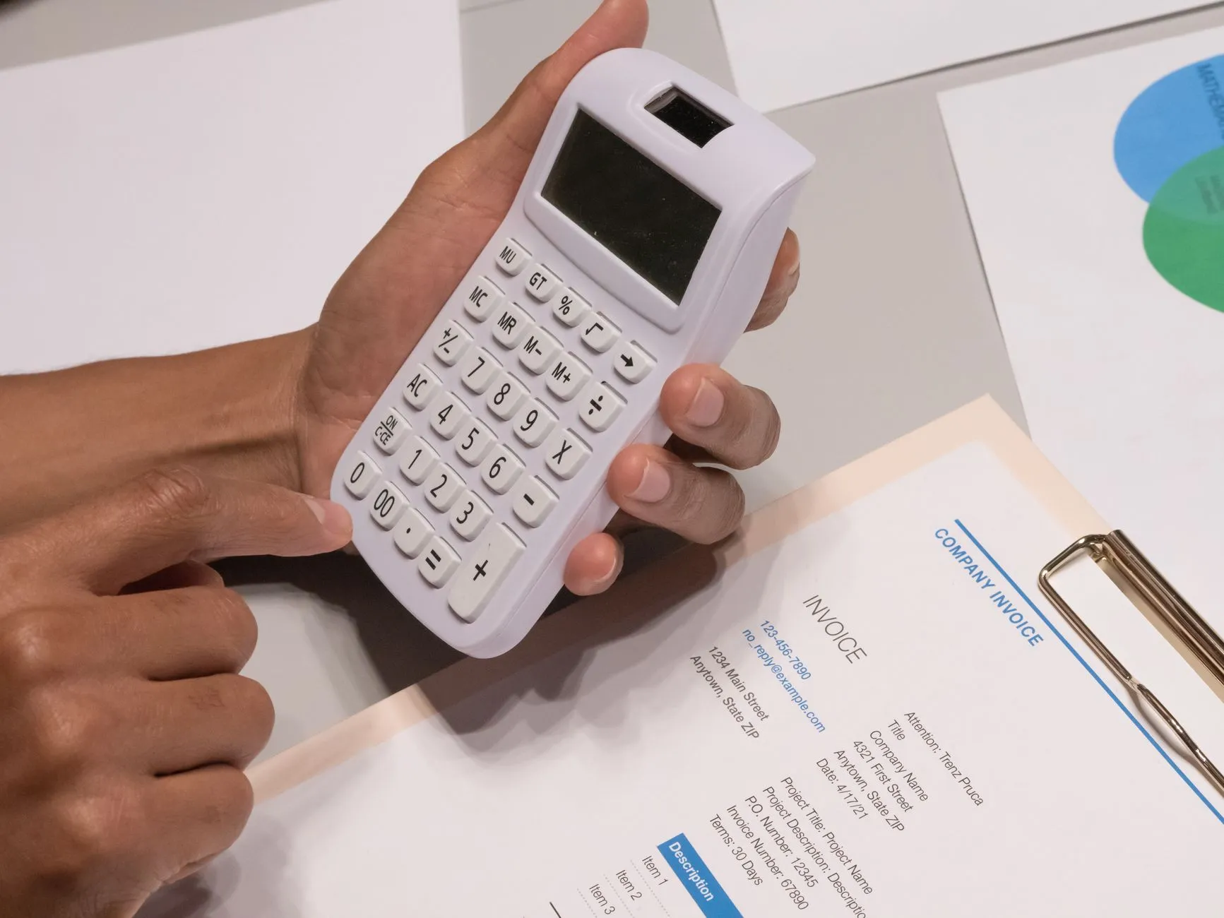 Hands using a calculator next to a printed invoice while working out SEO costs