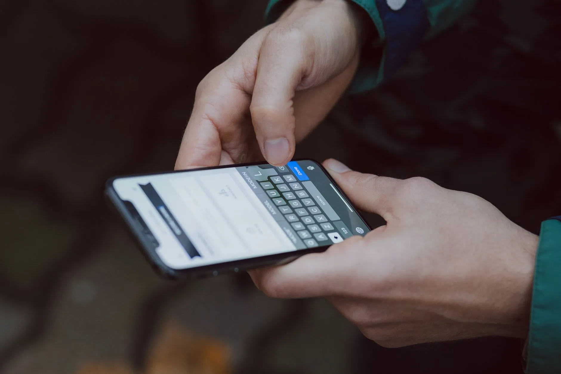 Hands typing a search on a smartphone keyboard, where both organic results and ads appear