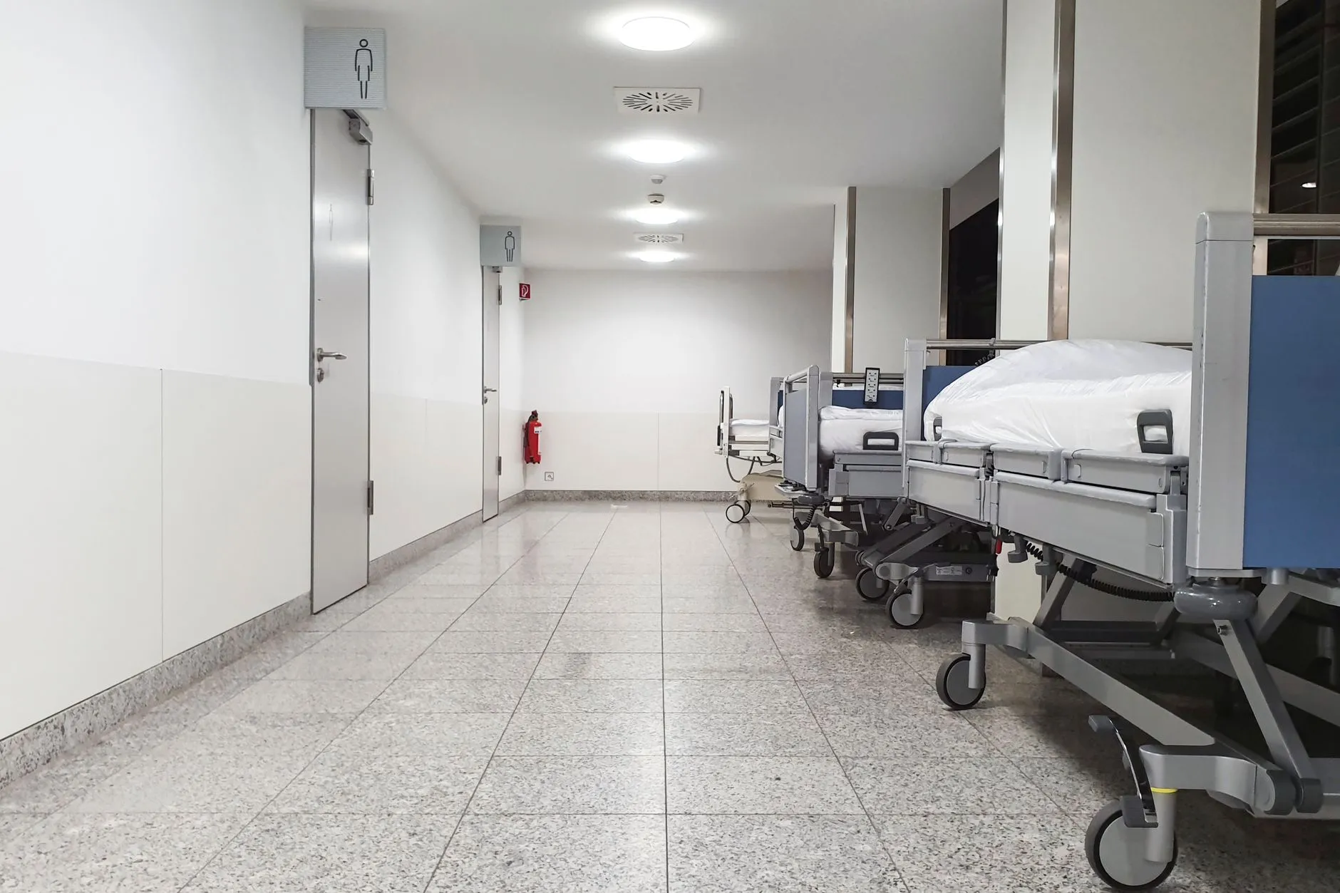 Empty hospital corridor with medical beds lined up under bright lights