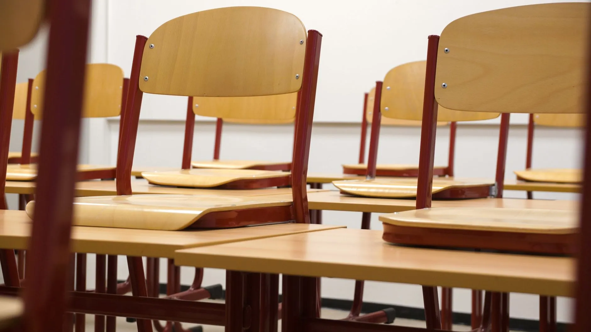 Empty classroom with wooden desks and chairs in neat rows