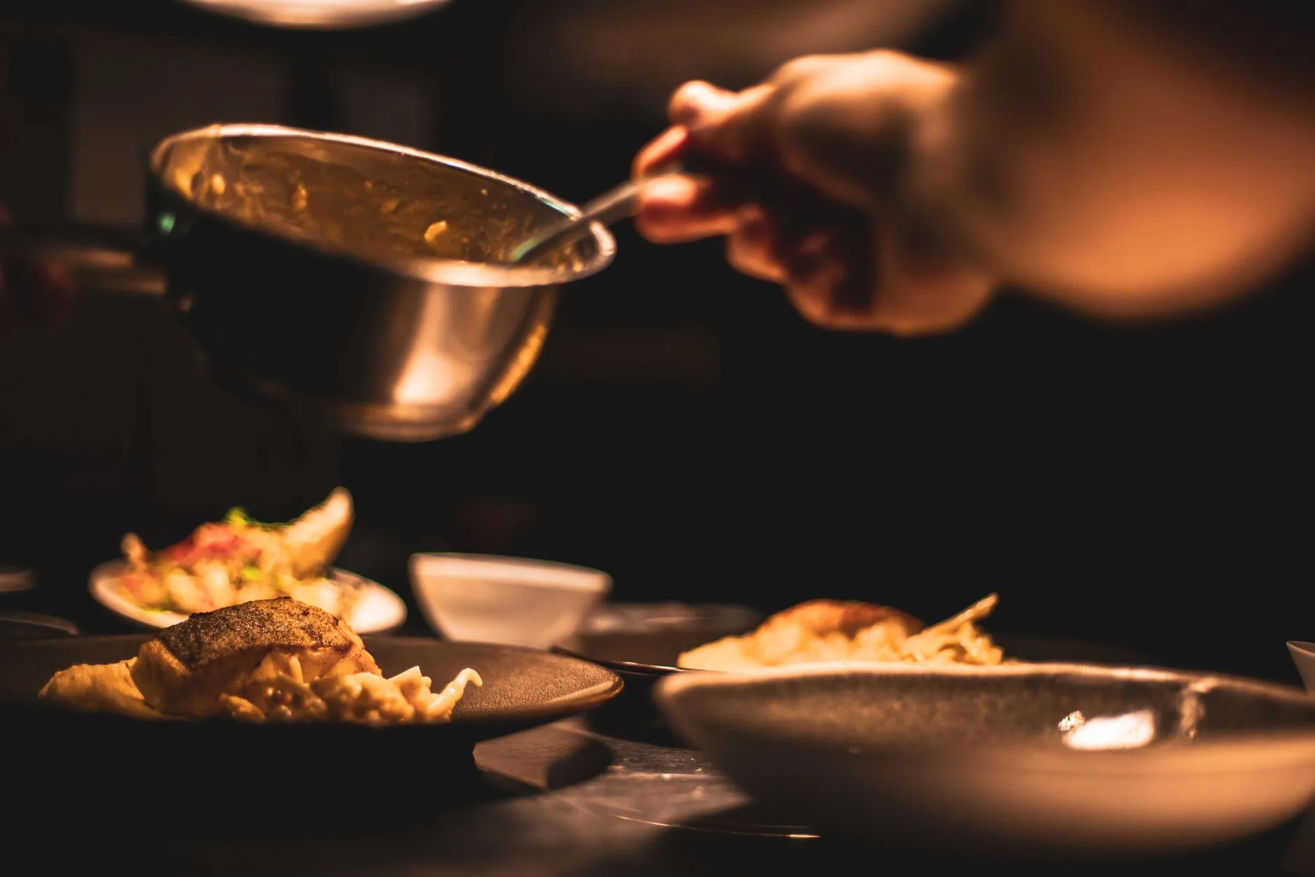Chef plating a dish in a dimly lit restaurant kitchen
