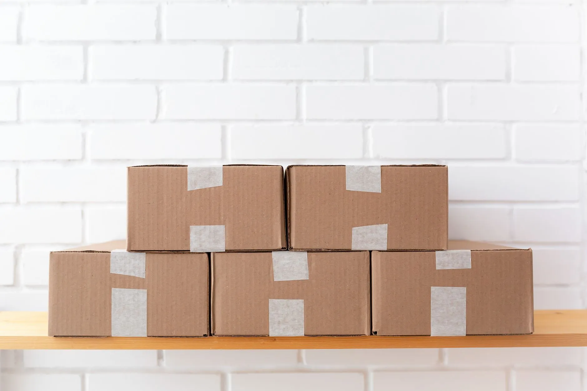 Taped cardboard boxes stacked on a wooden shelf, ready for ecommerce order dispatch